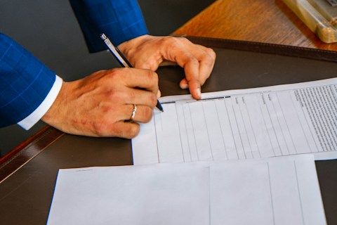person writing on white form paper